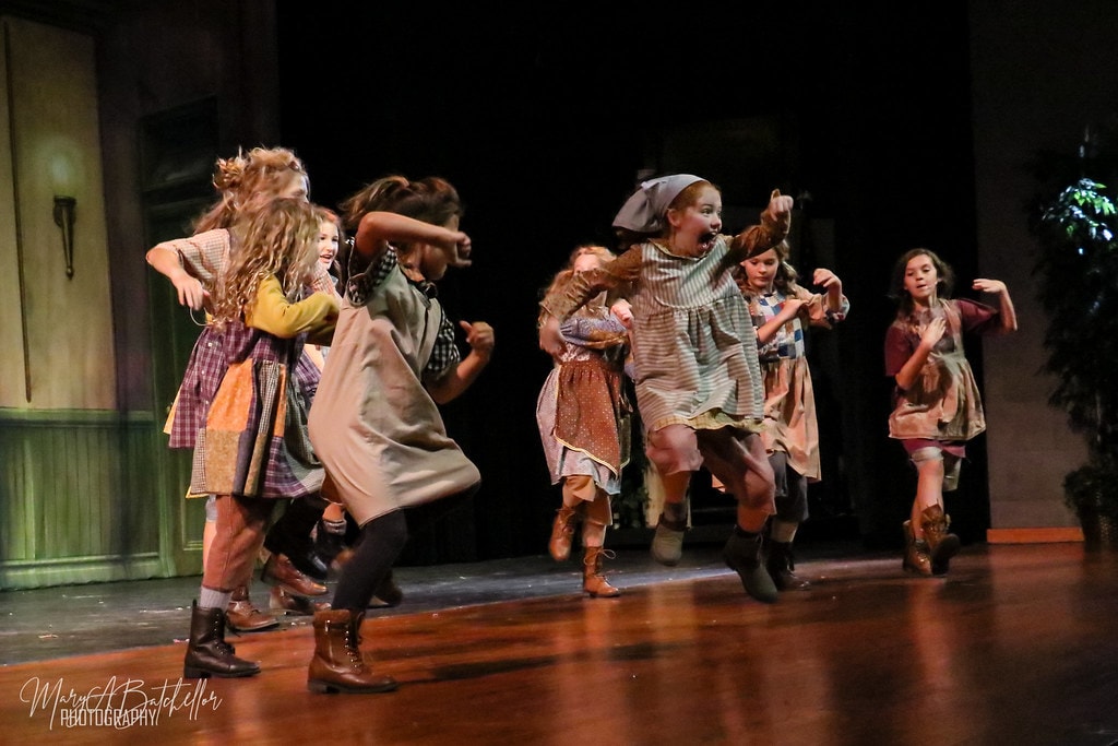 Annie — eight orphan girls stomp and dance energetically before the orphanage backdrop