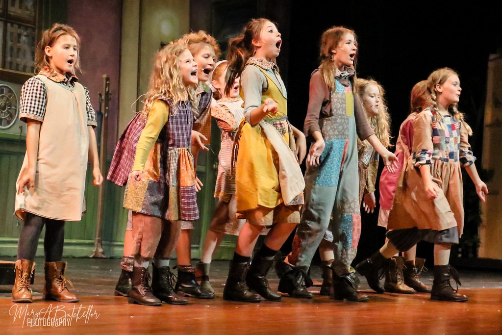 Annie — eight orphan girls sing with wide-open mouths in a powerful ensemble moment