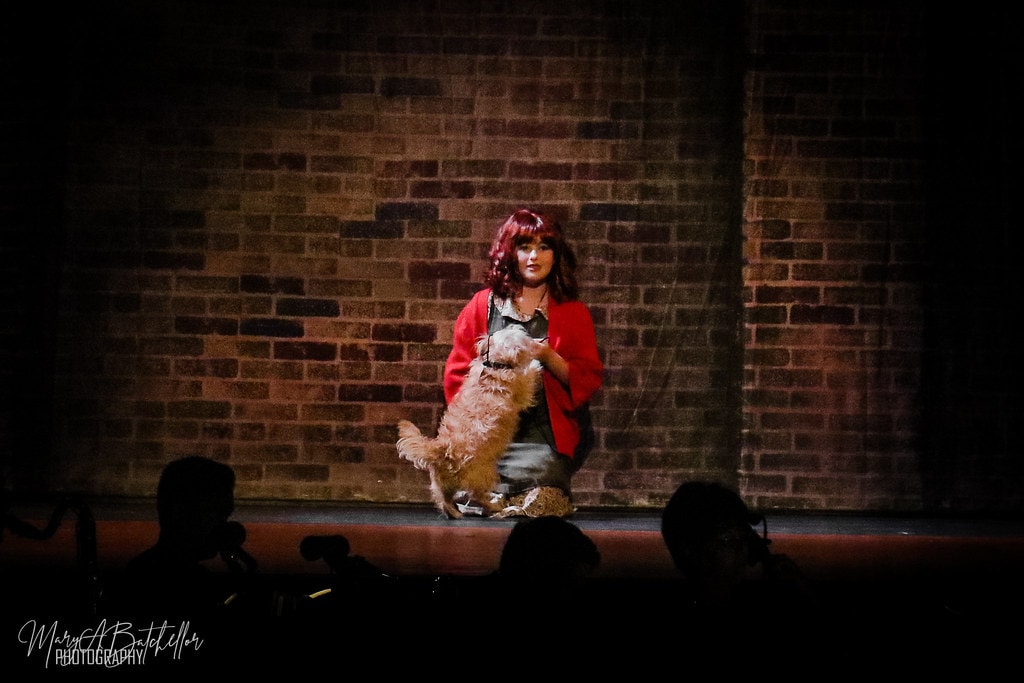 Annie — Annie in a red jacket holds Sandy the dog in a dramatic solo spotlight
