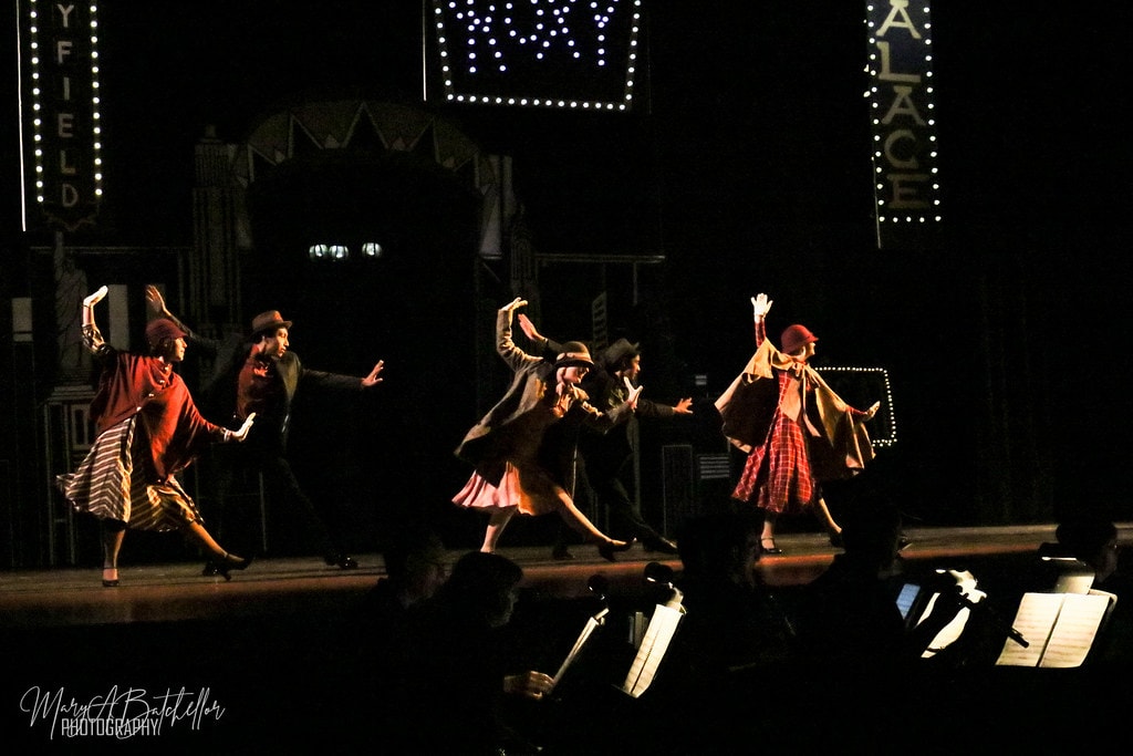 Annie — six performers dance energetically before vintage neon theater marquee signs