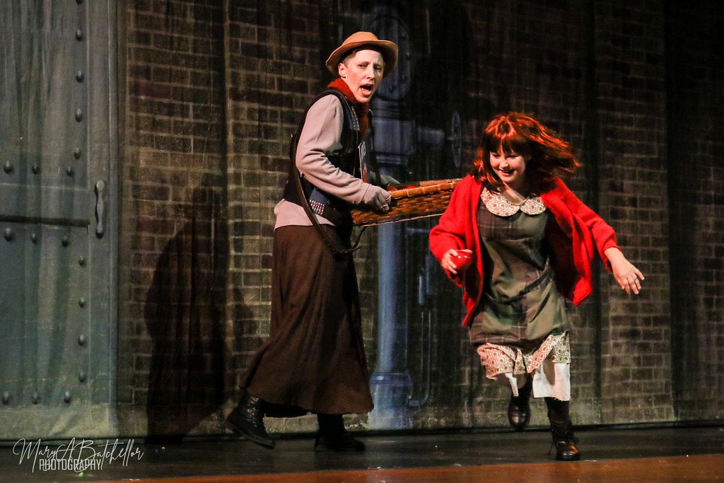 Annie — eight orphan girls hold mops and brooms singing in the orphanage set