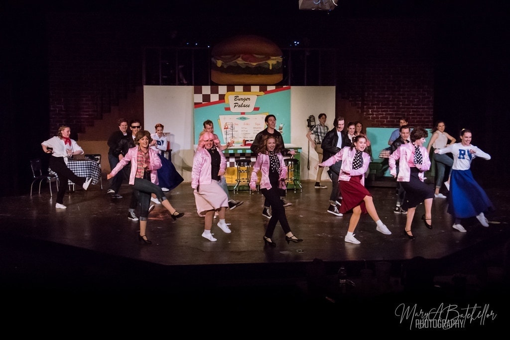 Grease — full cast with fists raised in triumphant finale