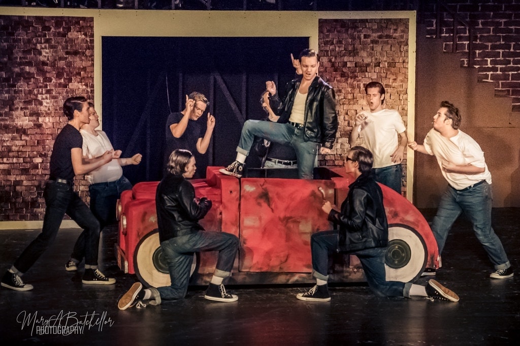 Grease — Danny on top of red car prop with T-Birds in dynamic poses