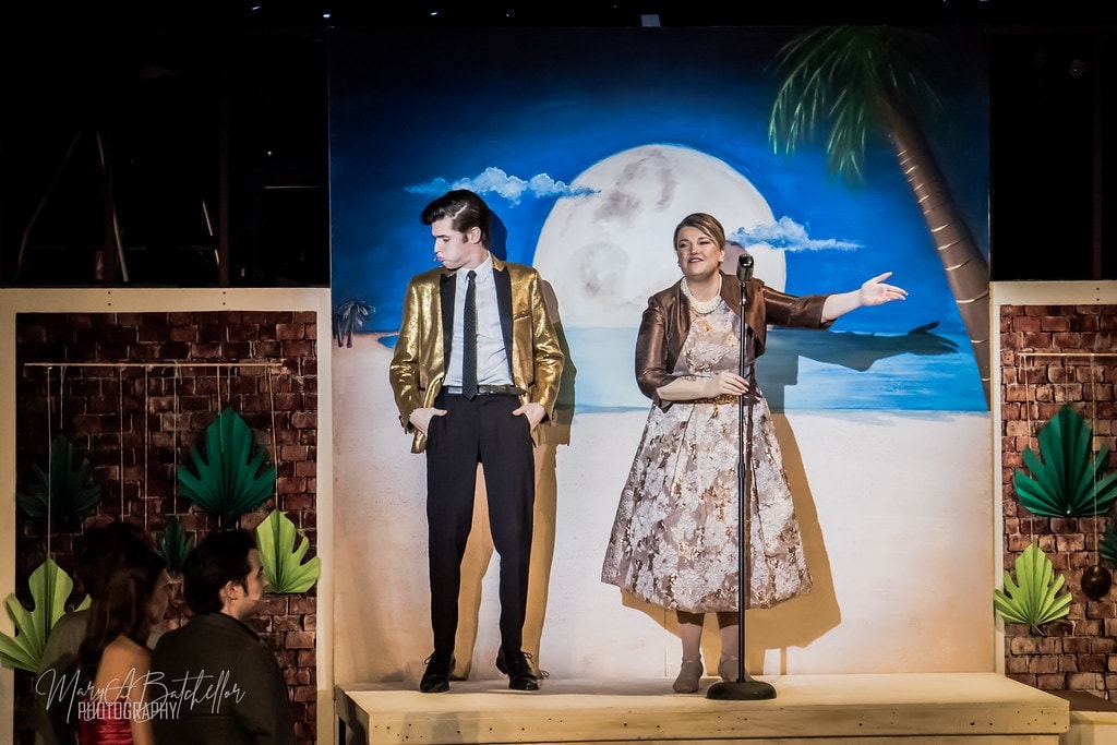 Grease — Teen Angel in gold jacket and woman at microphone