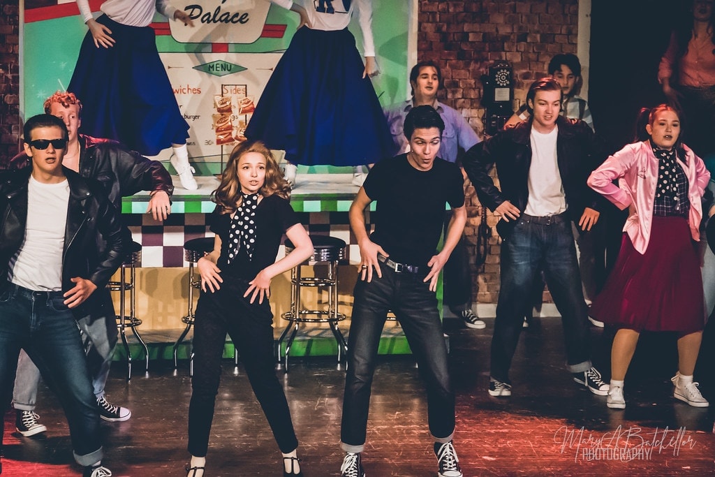 Grease — Sandy in polka-dot top and Danny in black leading dance