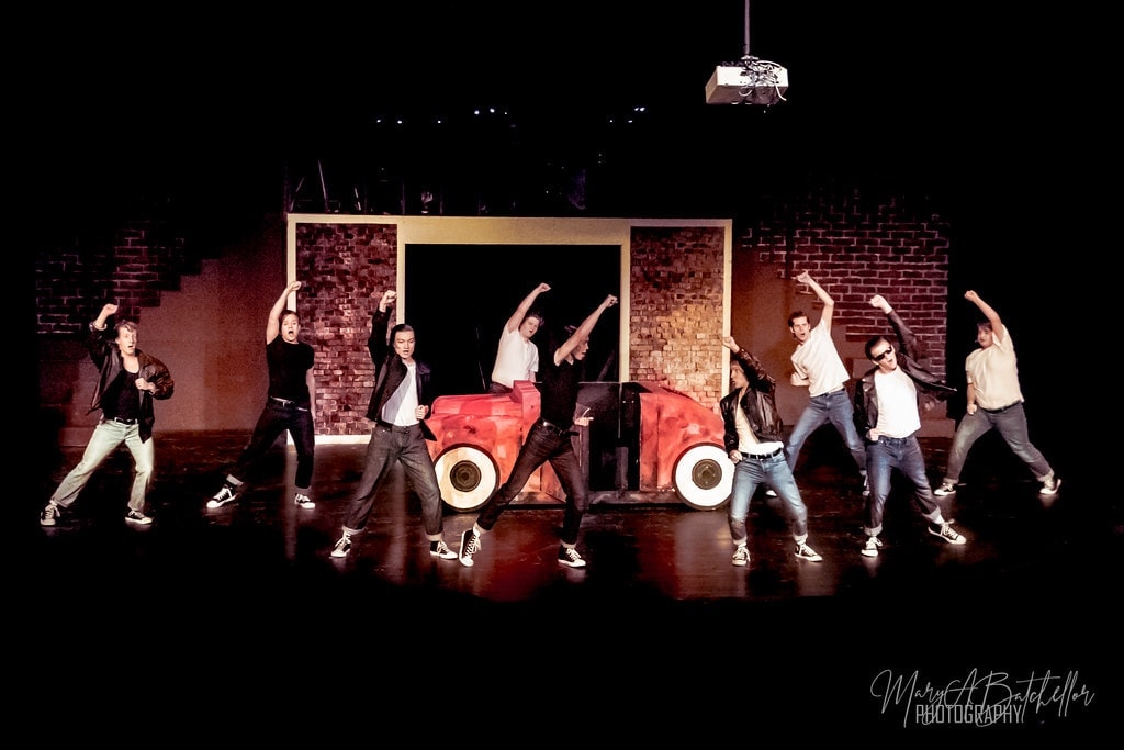 Grease — nine T-Birds in wide dramatic formation around the red car