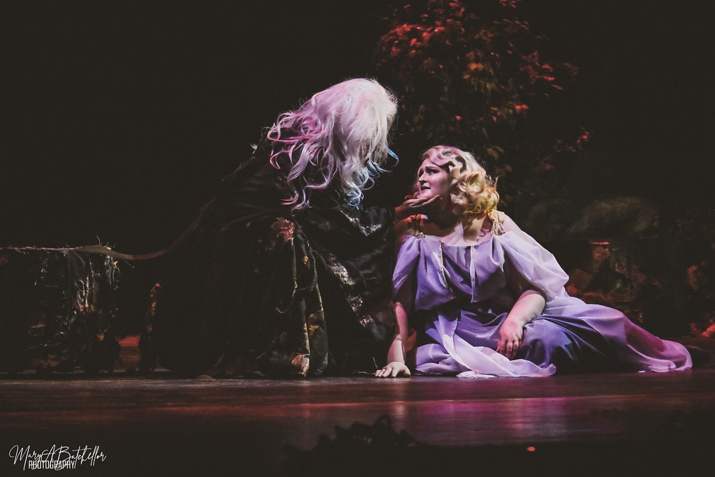 Into the Woods — the Witch looms over Rapunzel who sits on the stage floor in a lavender gown