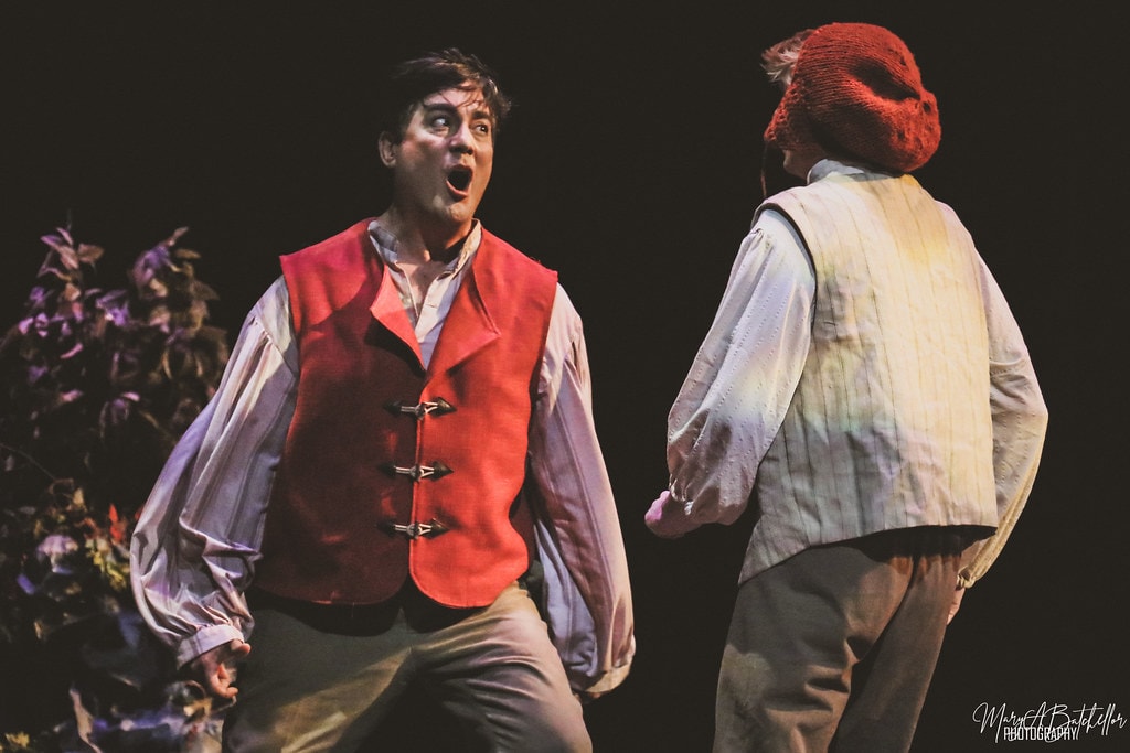 Into the Woods — the Baker in a red vest reacts with shock as Jack turns away in the dark forest