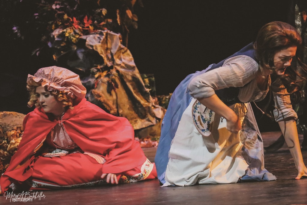 Into the Woods — the Witch in Act II robes belts a solo with one fist raised beside a glowing lantern