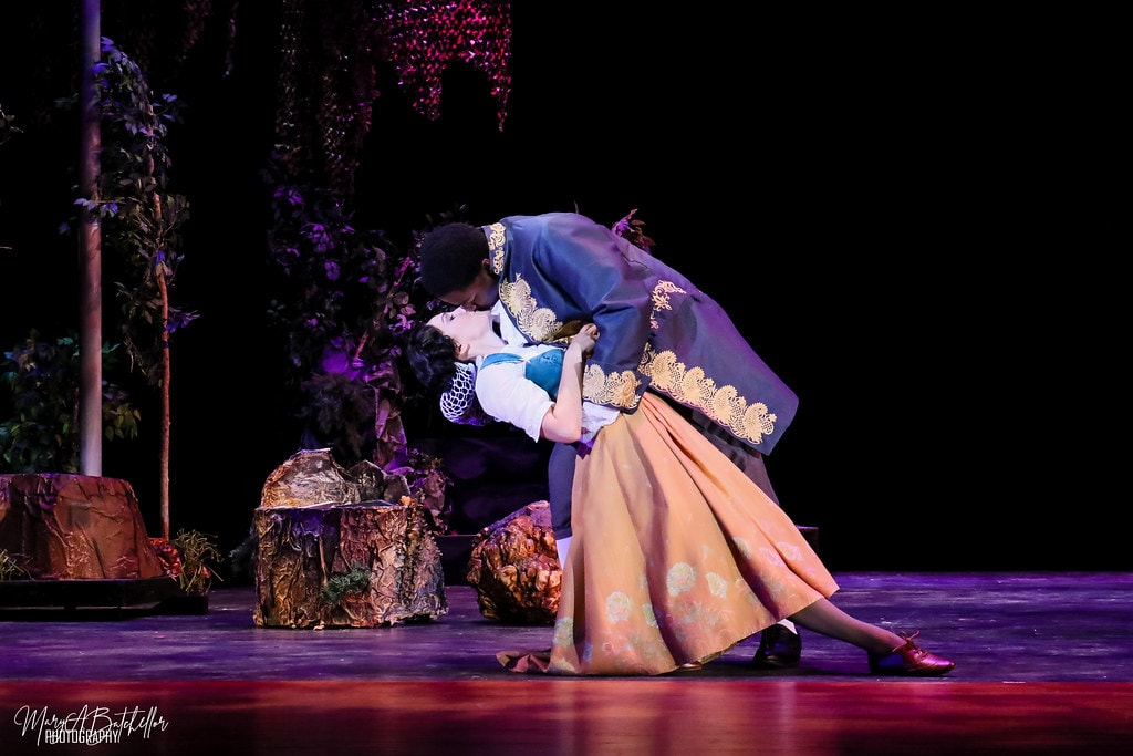 Into the Woods — Rapunzel's Prince dips Cinderella in a romantic embrace in the purple-lit forest