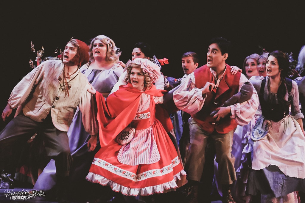 Into the Woods — the full ensemble reacts in shock with Little Red Riding Hood center stage in her red cape