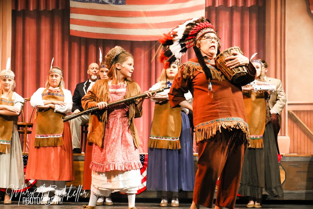 The Music Man — Amaryllis points a rifle at the Chief as the ensemble looks on
