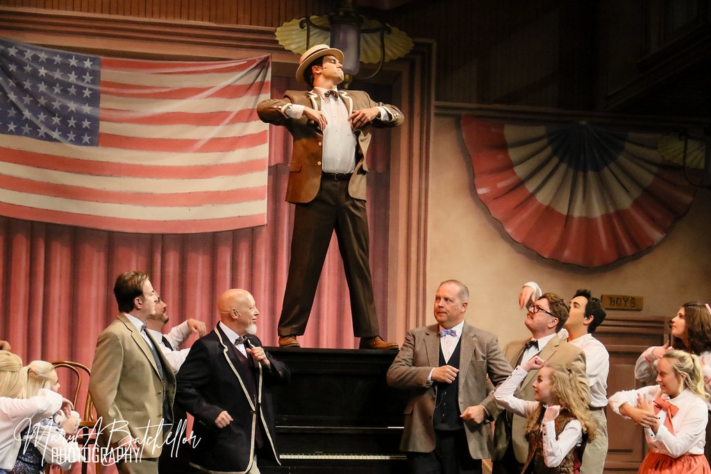 The Music Man — Harold Hill elevated on the piano as the full ensemble surrounds him