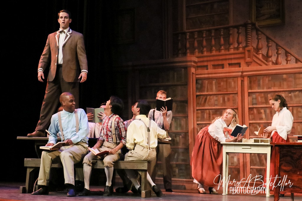 The Music Man — Harold Hill elevated on a desk as six students look up at him