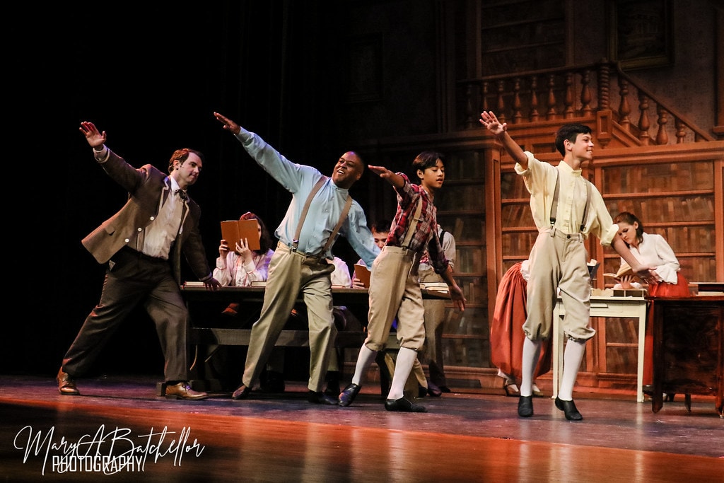 The Music Man — Harold Hill and three young men leap with arms outstretched in the library