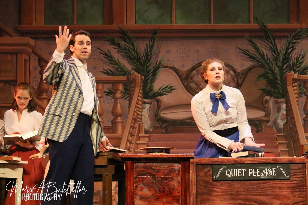 The Music Man — Harold Hill in a striped blazer gestures as Marian reacts at the library desk