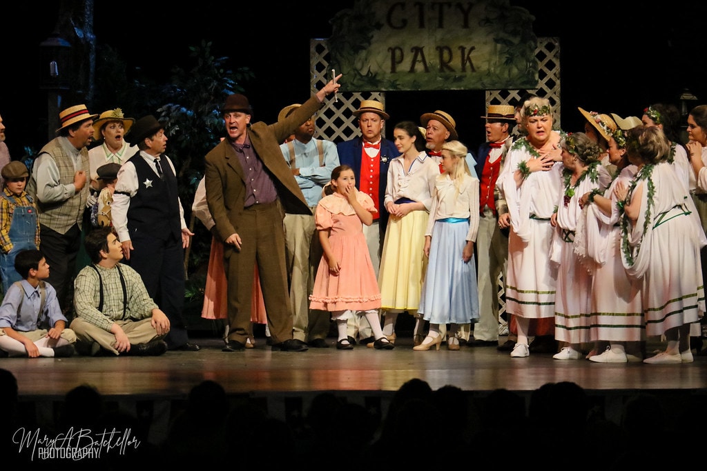 The Music Man — the full River City ensemble reacts in shock before the City Park sign