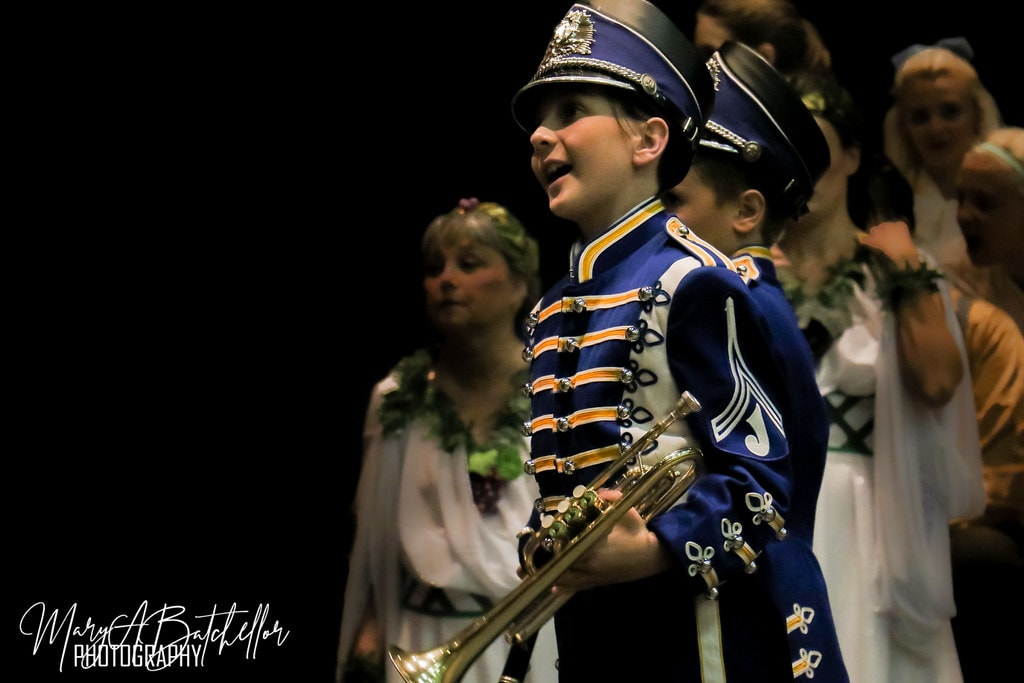 The Music Man — a young boy in a blue and gold marching band uniform holds a trumpet and sings
