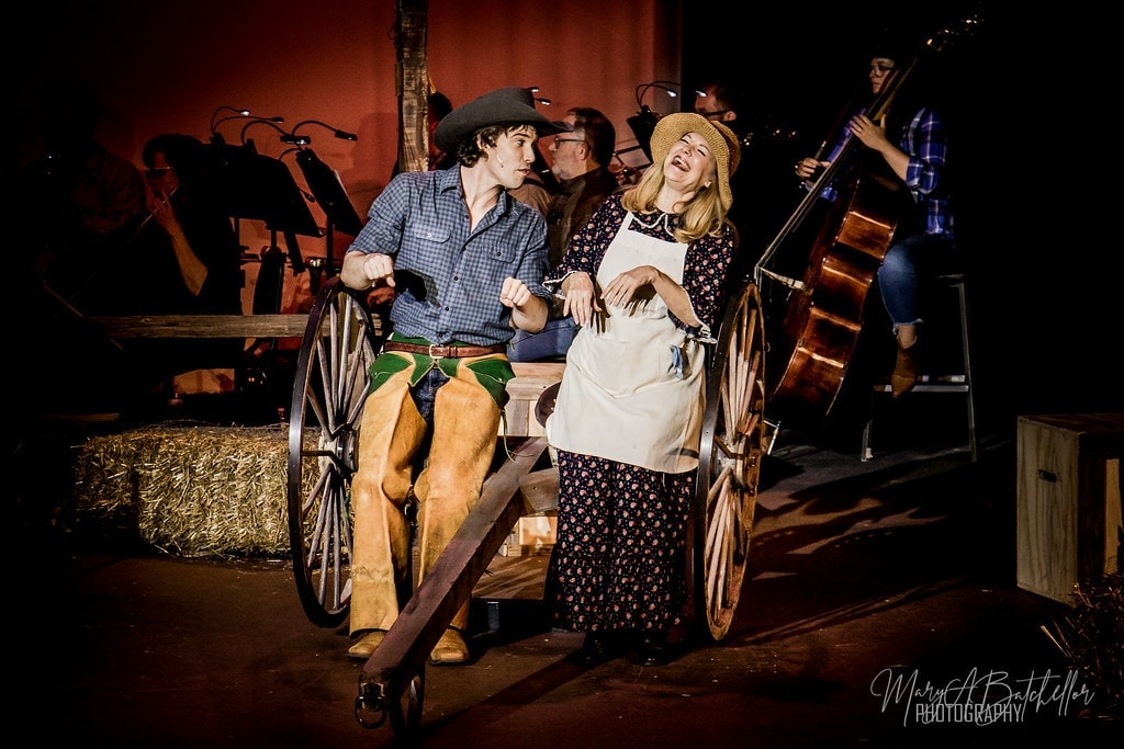 Oklahoma! — Curly lying on stage floor holding hat dramatically