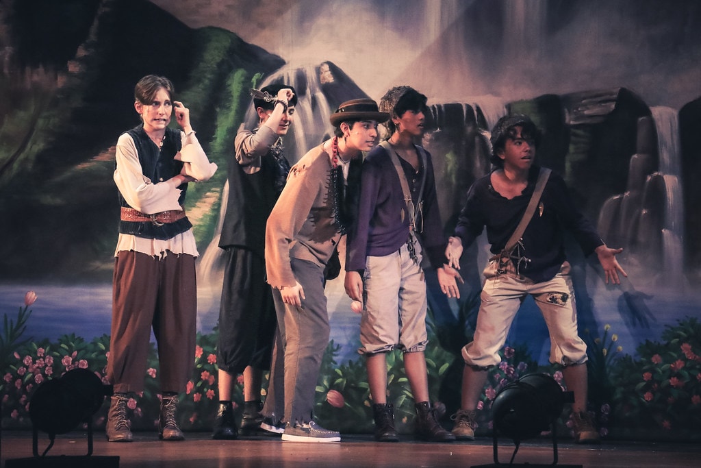 Peter Pan — five Lost Boys react in alarm before the Neverland waterfall backdrop