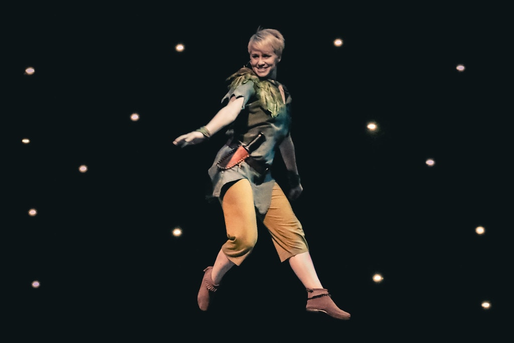 Peter Pan — Peter Pan smiles and strides confidently against a starlit black backdrop
