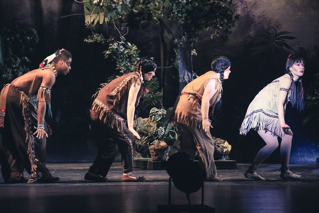 Peter Pan — four performers in Native American costumes creep in a crouched line across the jungle stage