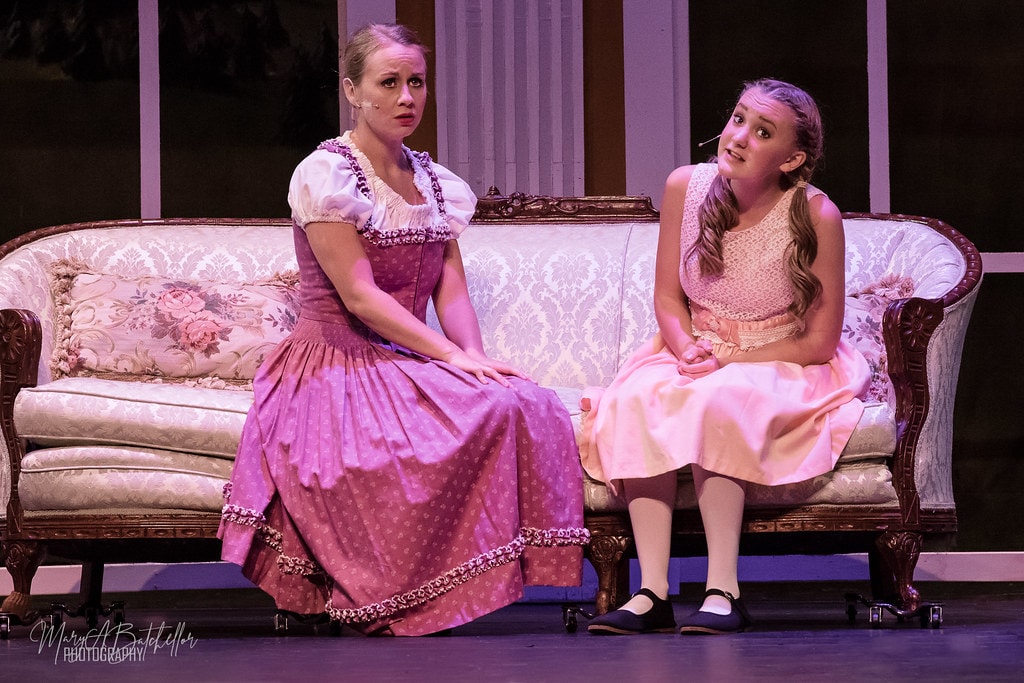 The Sound of Music — Maria in purple dirndl and Liesl in pink dress on the sofa