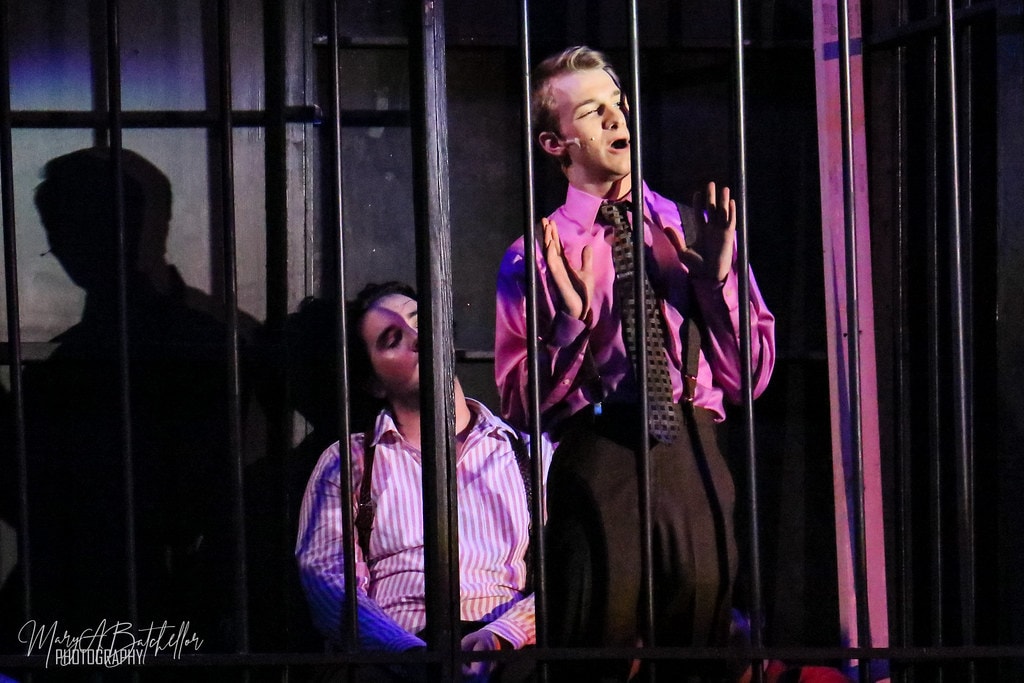 Thoroughly Modern Millie — actors perform a dramatic scene behind prison bars