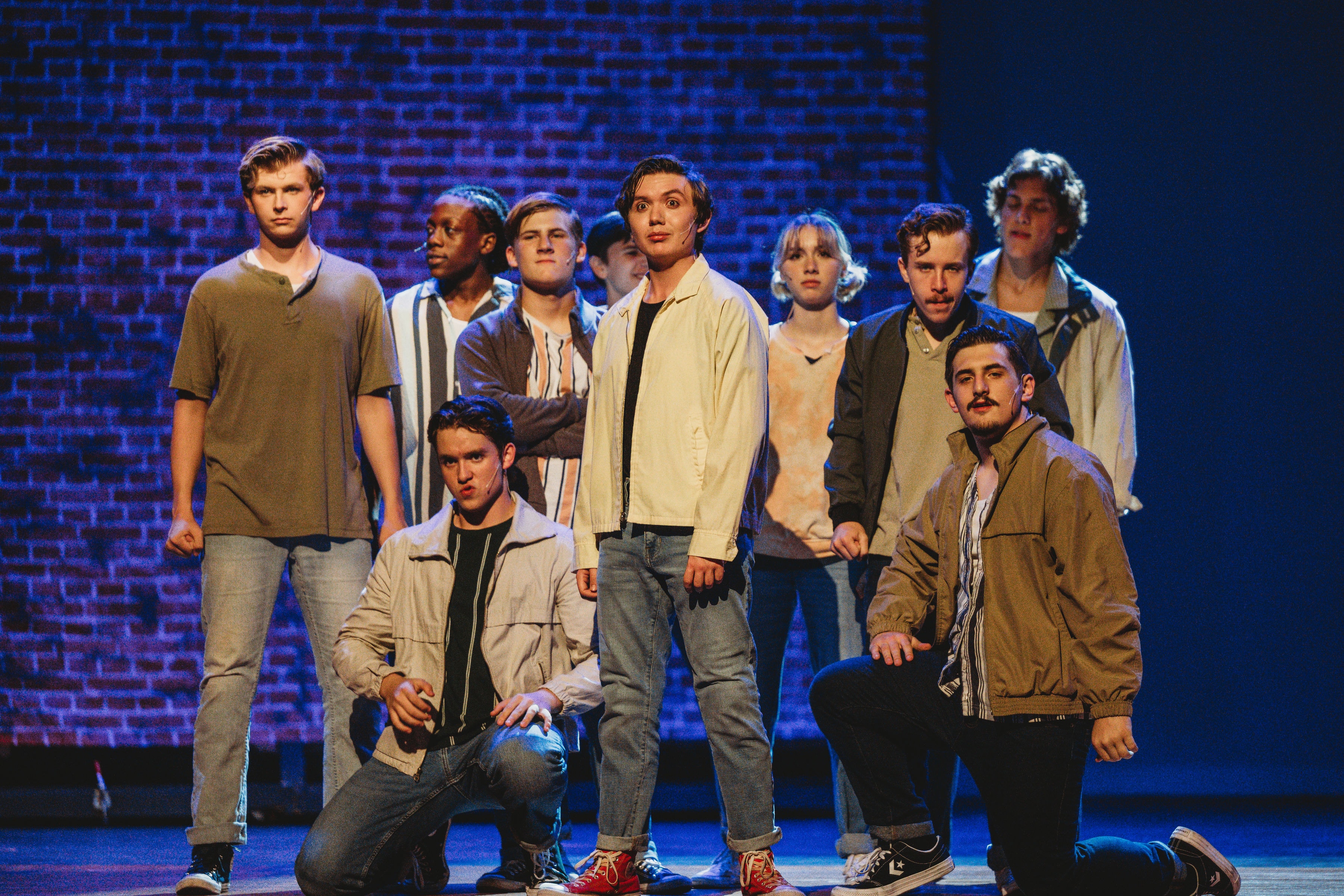West Side Story 2026 - Jets gang posed on stage with blue brick backdrop
