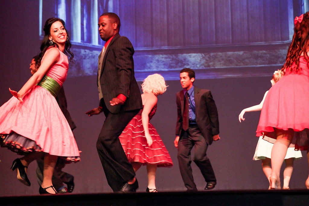 Couples dancing in 1950s costumes pink and black — West Side Story